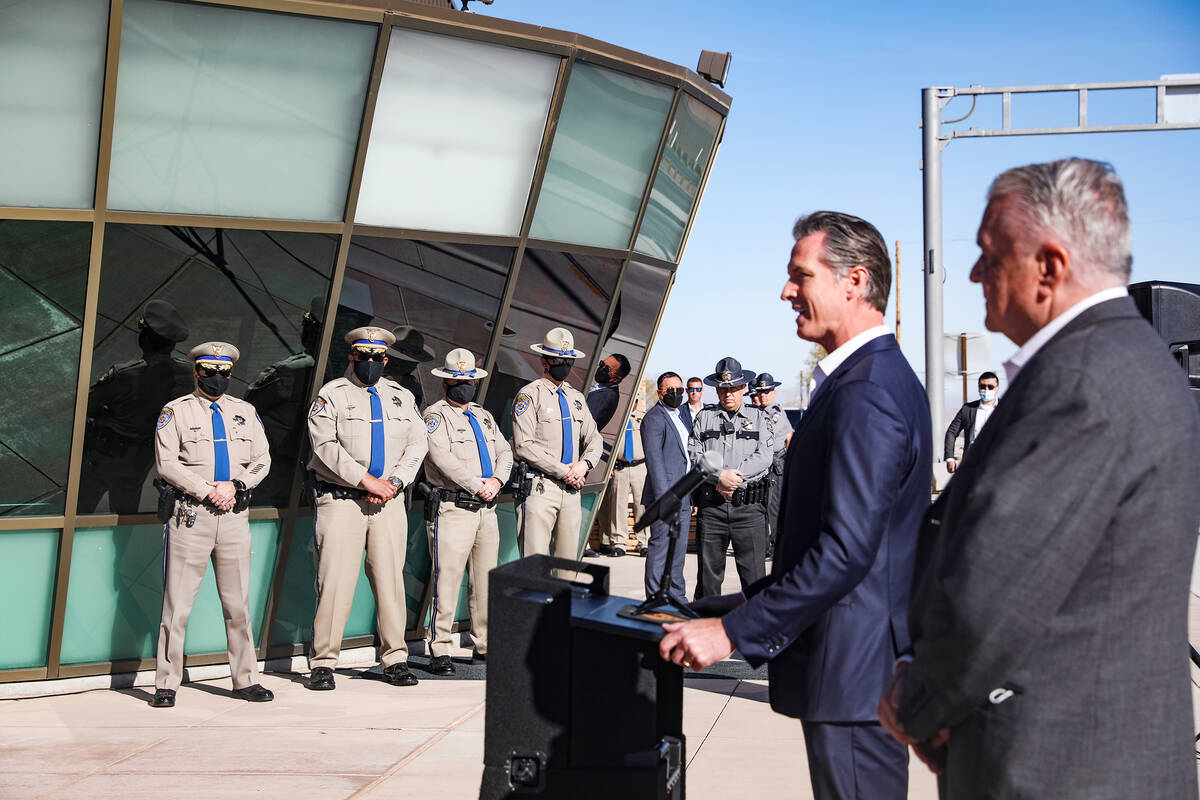 California Gov. Gavin Newsom addresses the media and as Nevada Highway Patrol troopers look on ...