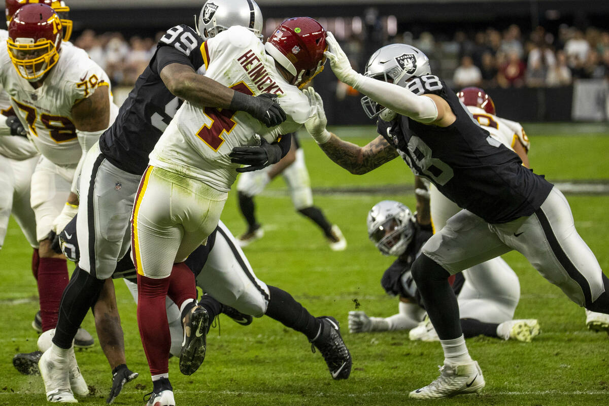 Raiders defensive end Clelin Ferrell (99) and defensive end Maxx Crosby (98) team up to take do ...