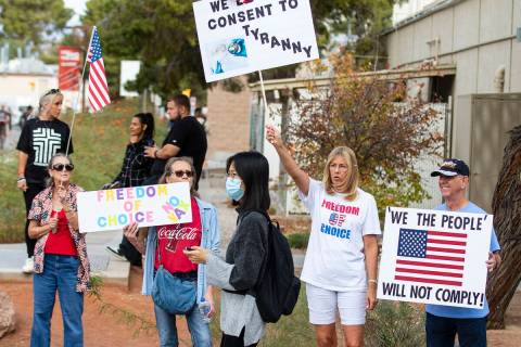 A UNLV student walks past people protesting the Nevada System of Higher Education’s vaccine m ...