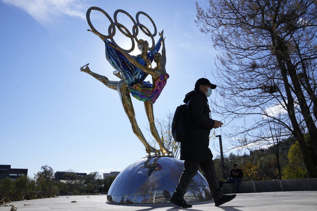 A visitor to the Shougang Park walks past the a sculpture for the Beijing Winter Olympics in Be ...