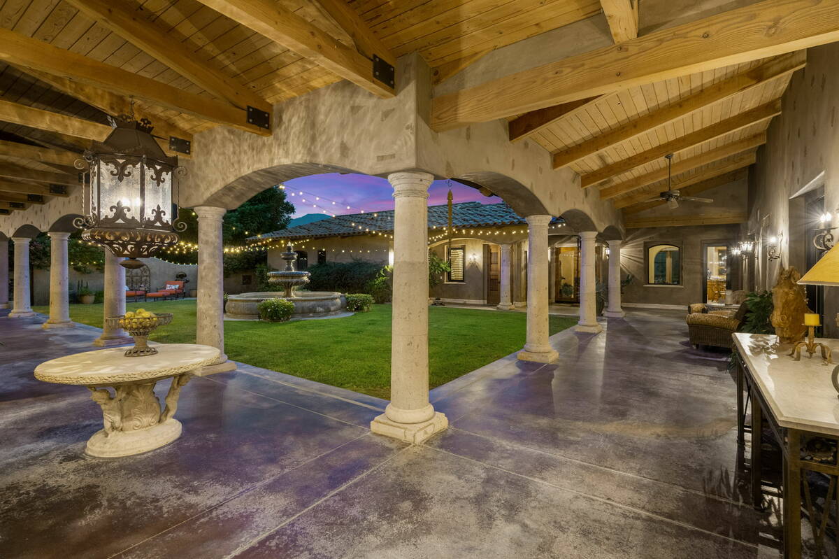 The hand-carved wood main gate leads to a grand courtyard with an oversized custom stone water ...