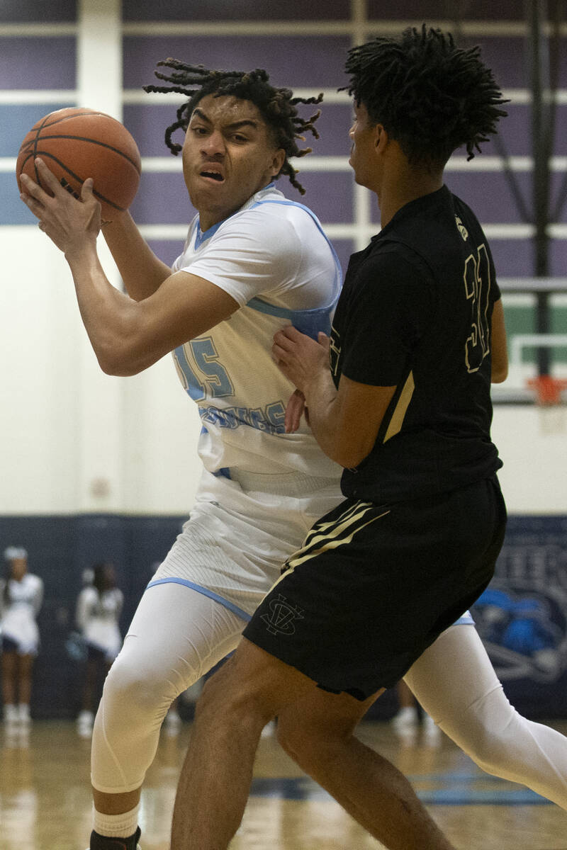 Canyon Springs forward Jalen Foy (15) is defended by Spring Valley guard Alijah Adem (31) durin ...