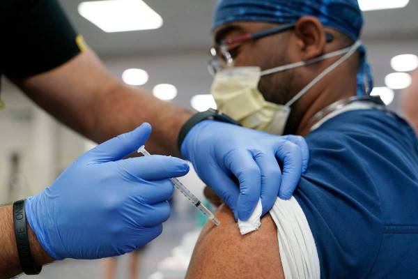 A healthcare worker receives a Pfizer COVID-19 booster shot at Jackson Memorial Hospital Tuesda ...