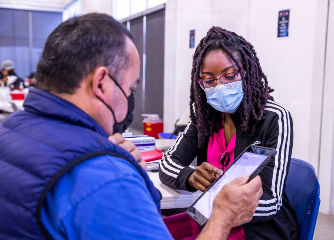 Jose Grajeda, left, verifies his data with Adwoa Fosu who will give him a shot in the COVID-19 ...