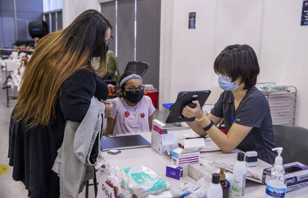 (From left) Grace Perez helps to verify the data of Noemi Flores Perez, 9, as Grisly Guerrero p ...