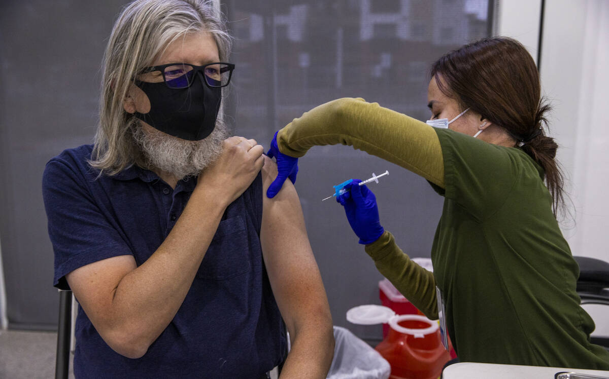 Michael Homa, left, receives a shot from Mary Aldana to while in the COVID-19 vaccination clin ...