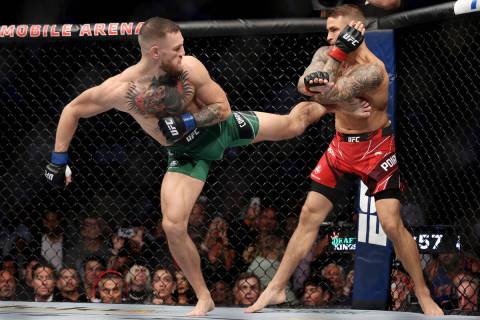 Conor McGregor, left, kicks Dustin Poirier in the first round of a lightweight bout against Dus ...