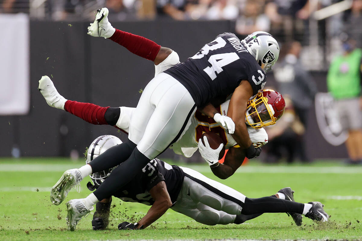 Raiders outside linebacker K.J. Wright (34) and cornerback Nate Hobbs (39) tackles Washington F ...