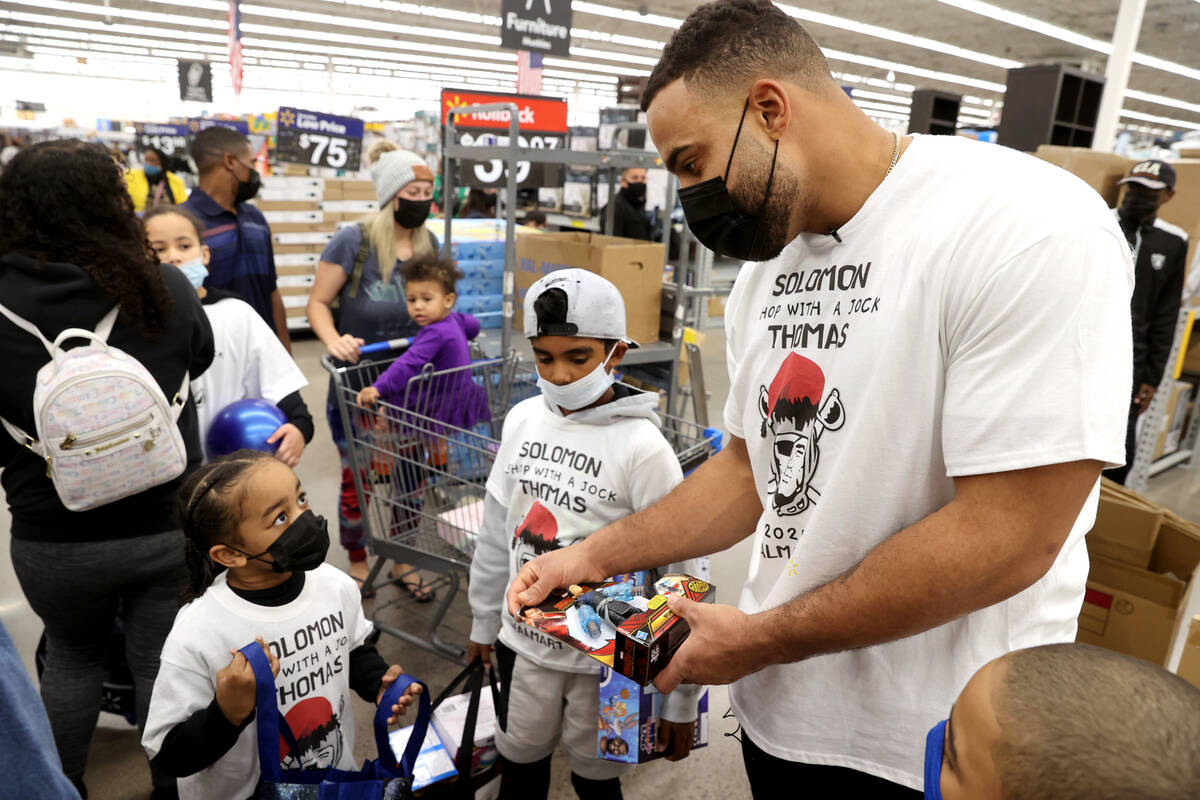 Raiders defensive tackle Solomon Thomas shops with Kai Hooks, 6, left, and Jabron Jones, 11, du ...