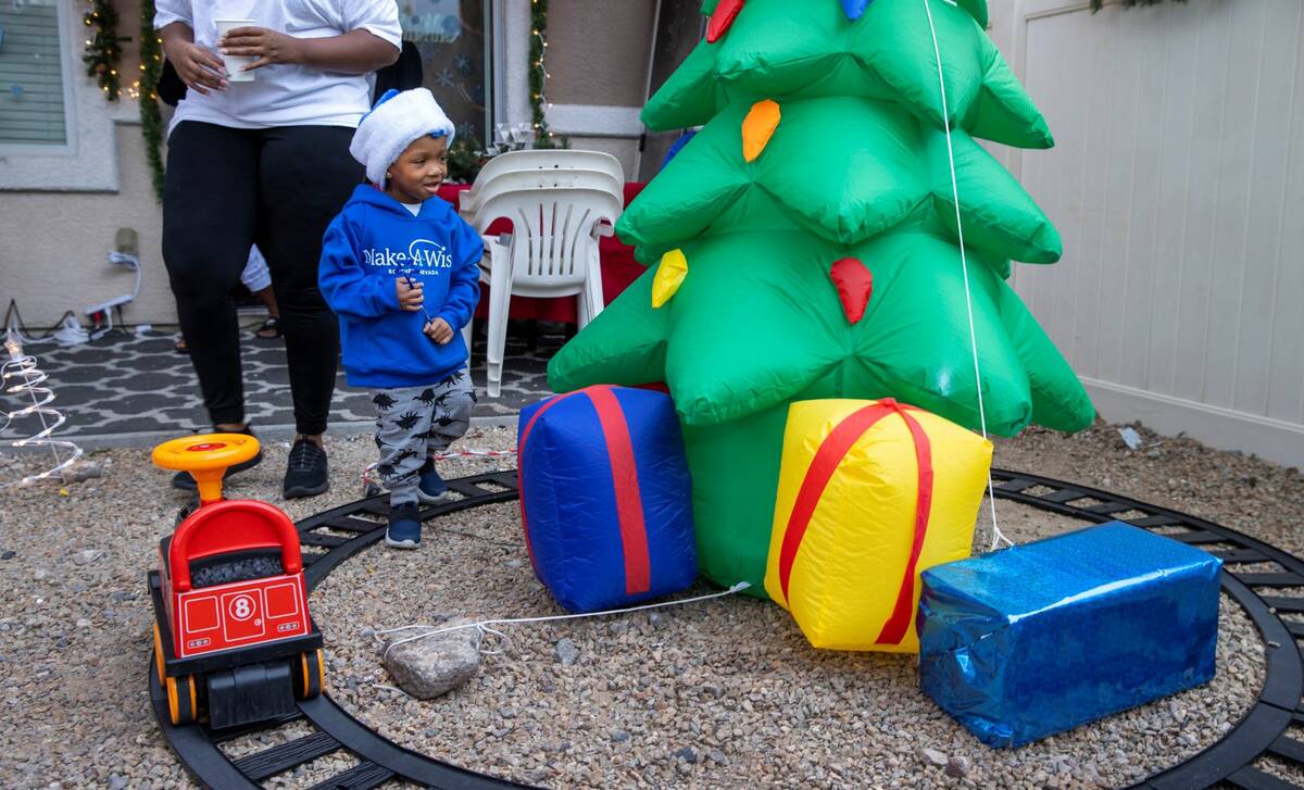 Aayden Hobbs, 3, a heart transplant recipient, checks out a tree and electric train on the trac ...