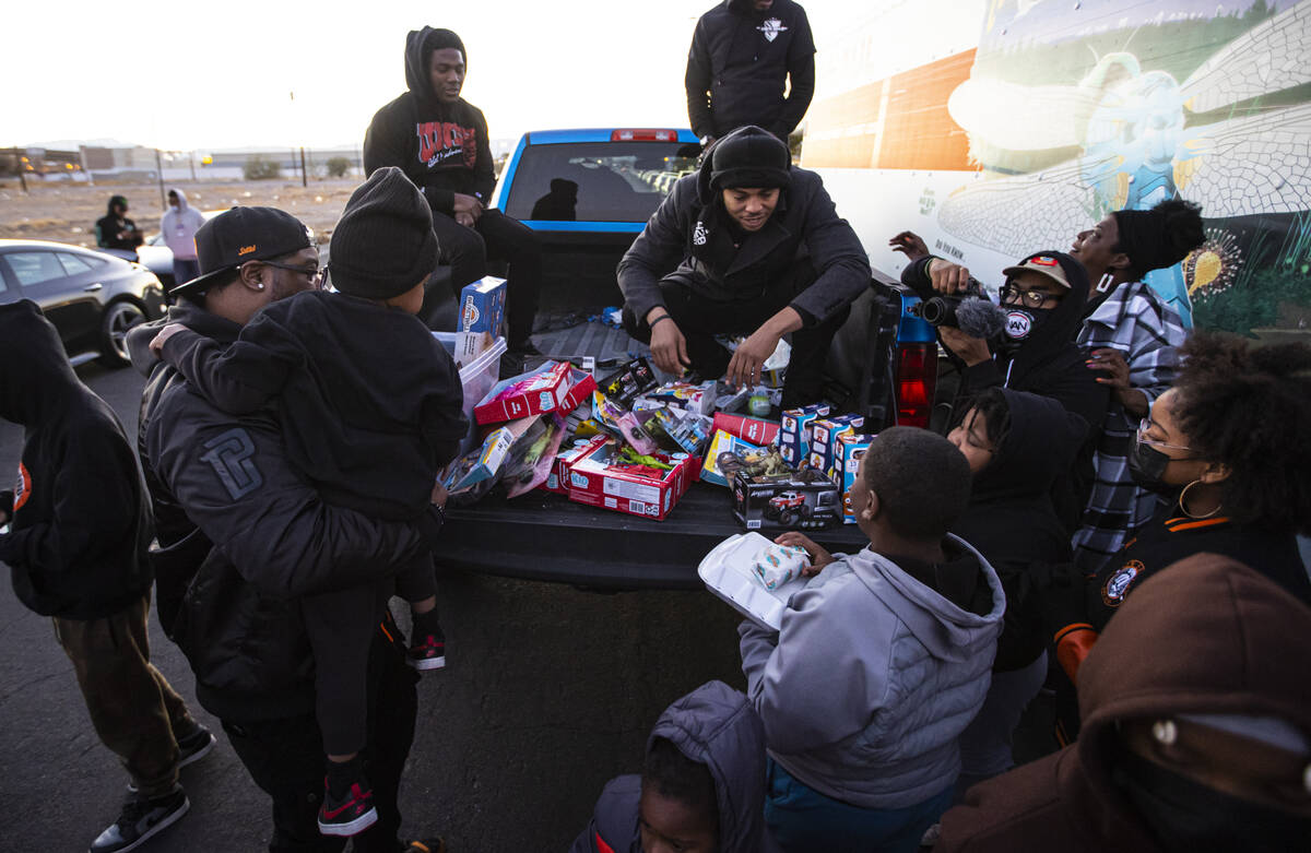 Kito Ford, of New Era Nation Atlanta chapter, right, hands out toys to children during a commun ...