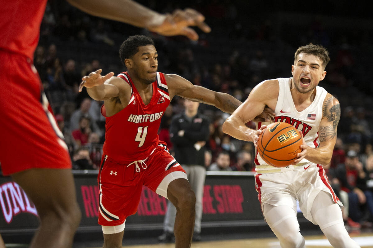 UNLV Rebels guard Jordan McCabe (5) drives around Hartford Hawks guard Moses Flowers (4) during ...