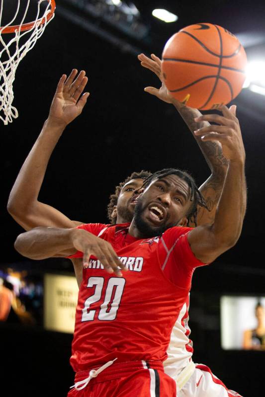 Hartford Hawks guard Austin Williams (20) and UNLV Rebels forward Royce Hamm Jr. (14) jump for ...