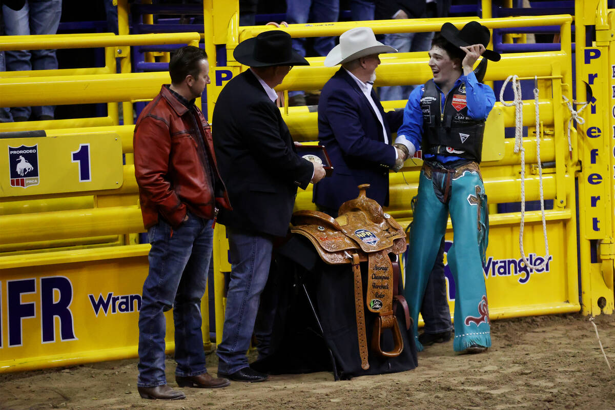 Jess Pope of Waverly, Kan., far right, is presented with a gold buckle after his win in the bar ...