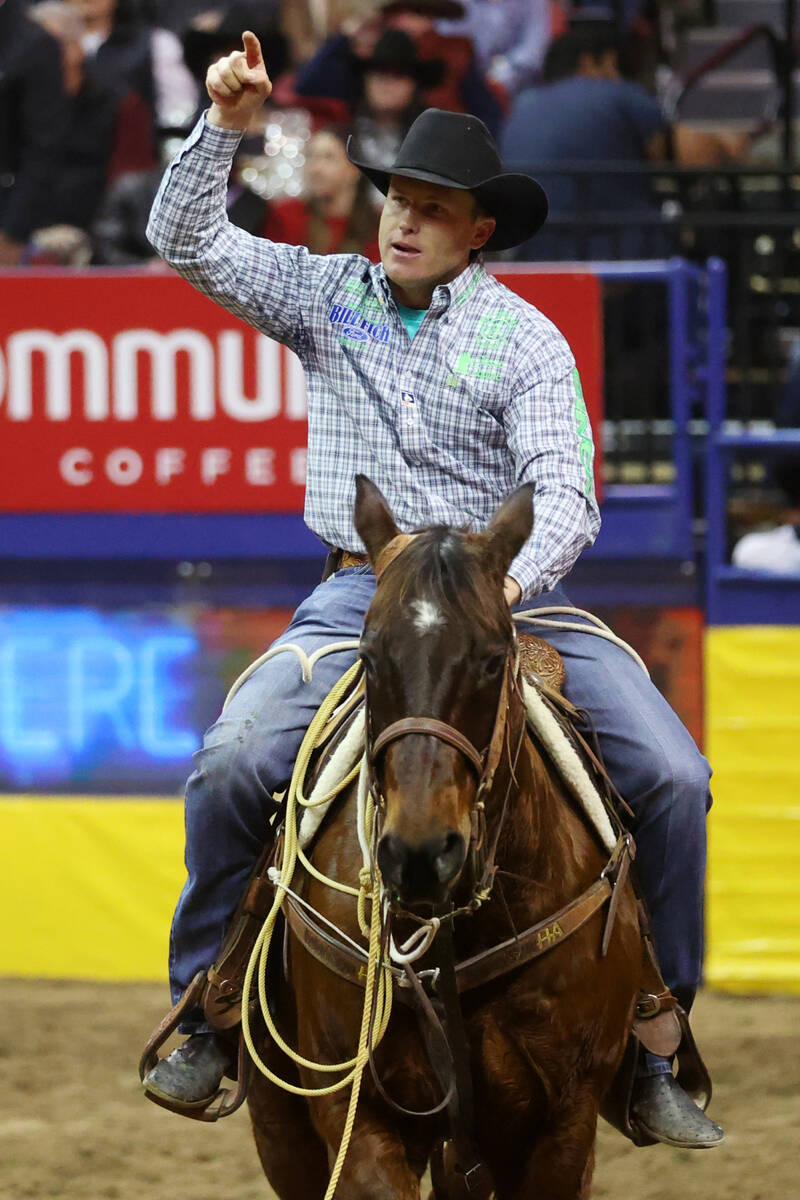 Caleb Smidt of Belville, Texas, raises his hand after his run in the tie-down event during the ...