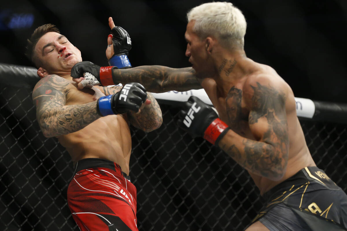 Charles Oliveira, right, lands a punch against Dustin Poirier during a lightweight mixed martia ...