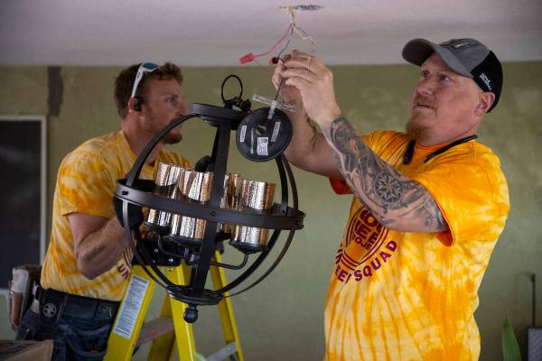 Volunteers Kyle Taylor, left, and Chad Scott, install a new light fixture as part of a home ren ...