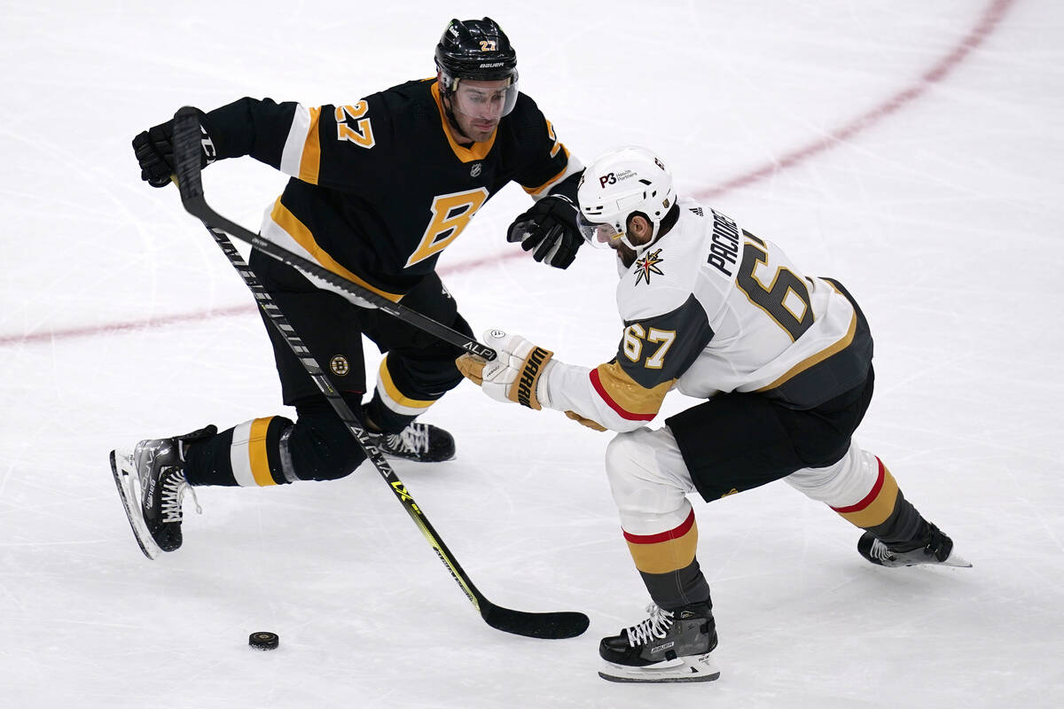 Boston Bruins defenseman John Moore (27) checks Vegas Golden Knights left wing Max Pacioretty d ...