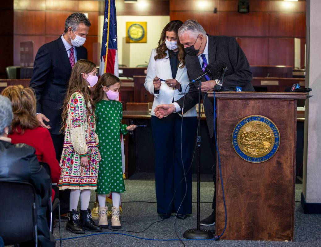 Gov. Steve Sisolak, from right, gives out ceremonial pens after signing the official document a ...