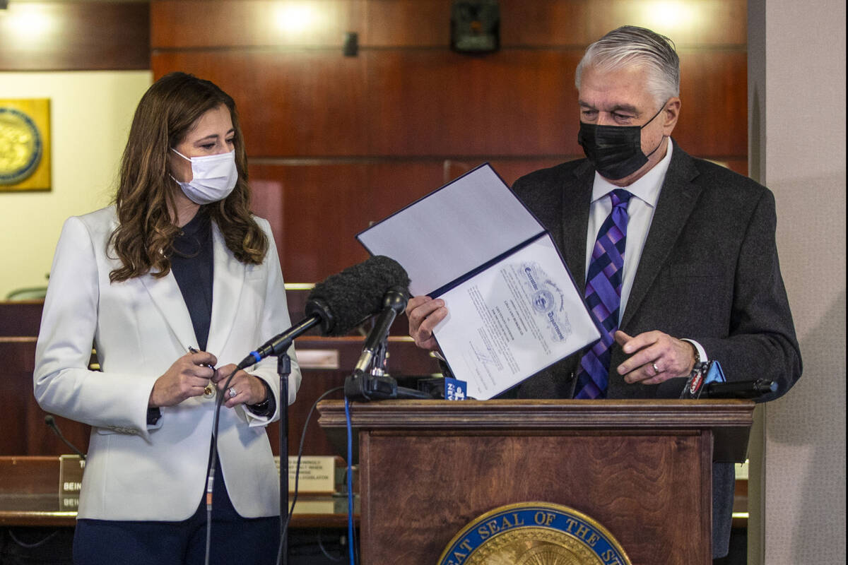 Gov. Steve Sisolak shows the official document he just signed to appoint Lisa Cano Burkhead as ...