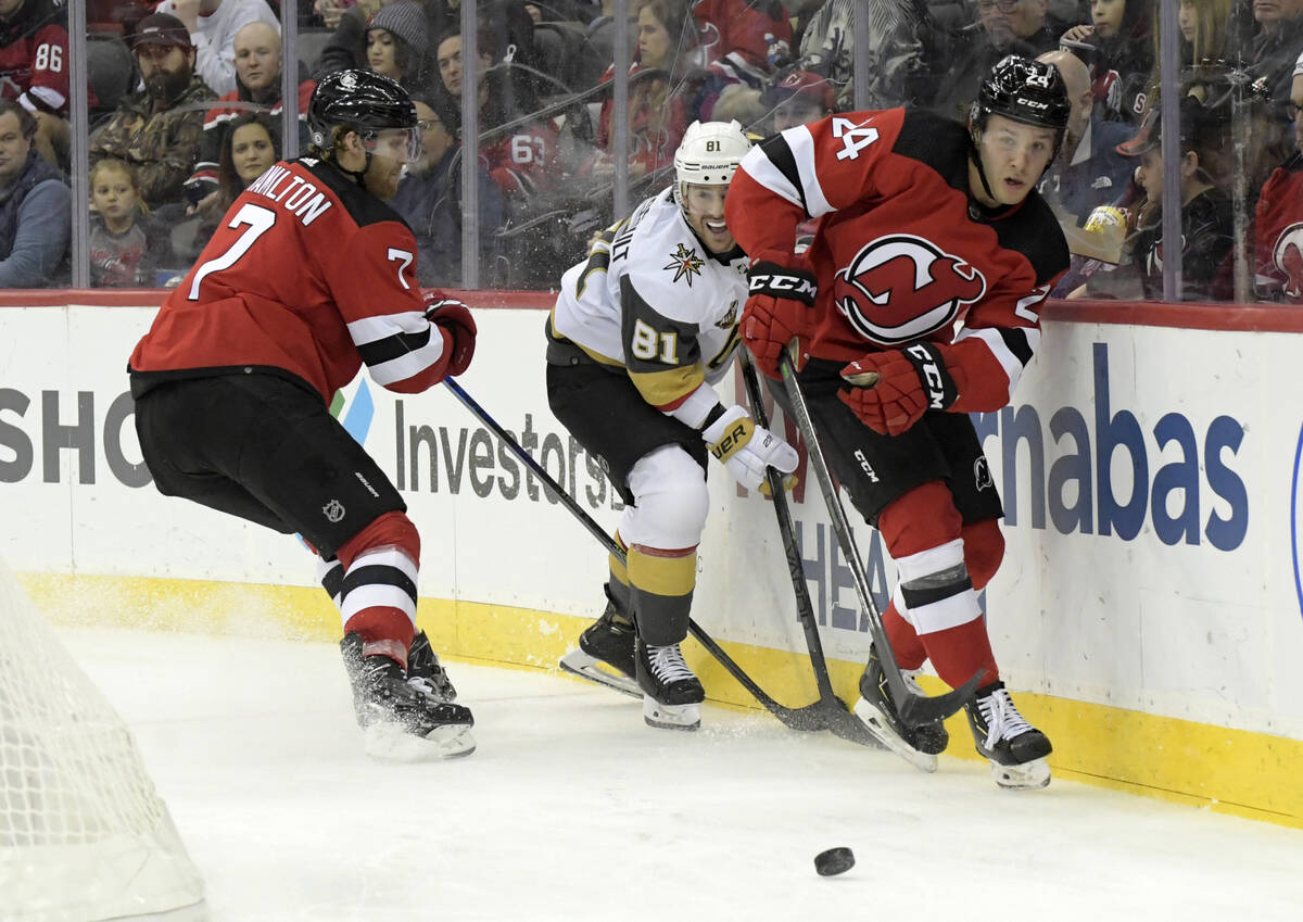 New Jersey Devils defenseman Ty Smith (24) chases the puck as Vegas Golden Knights center Jonat ...