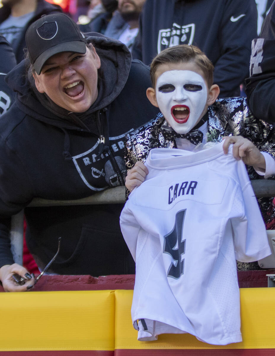 A young Raiders fan holds up a Derek Carr jersey before an NFL football game against the Kansas ...
