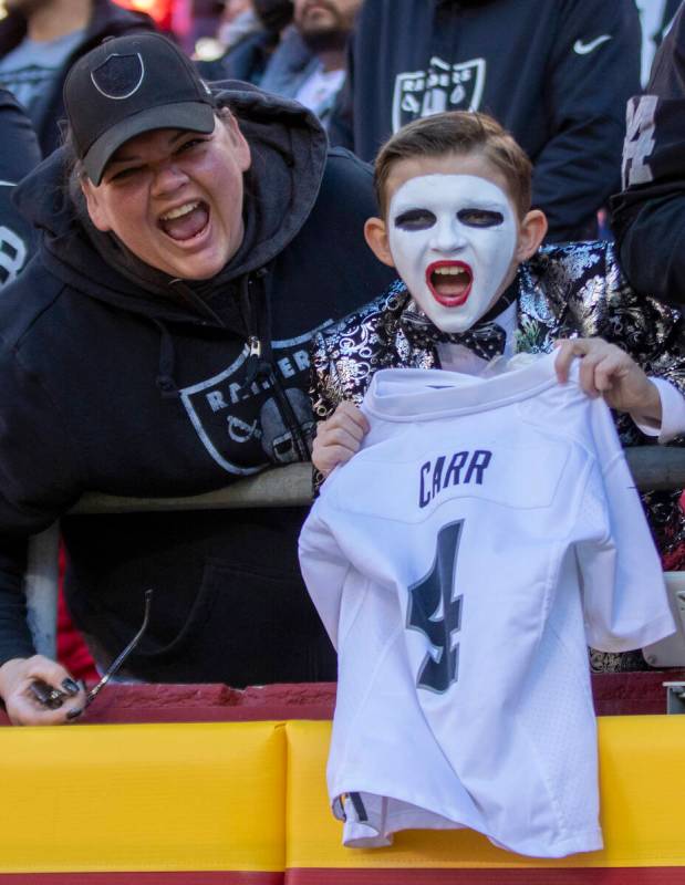 A young Raiders fan holds up a Derek Carr jersey before an NFL football game against the Kansas ...