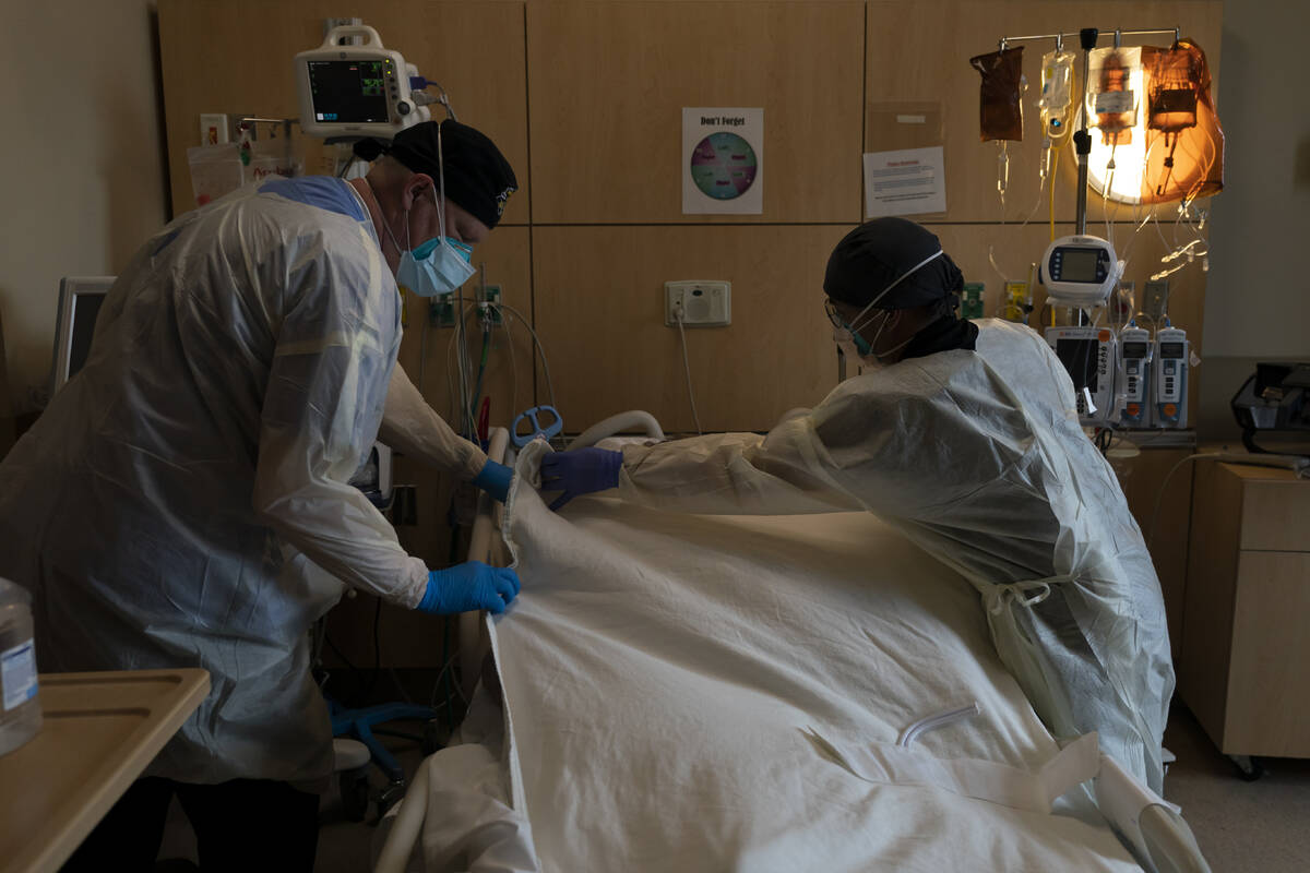 Respiratory therapist Frans Oudenaar, left, and registered nurse Bryan Hofilena cover a body of ...