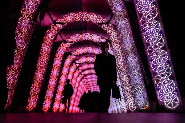 People walk through a tunnel of the holiday light displays Thursday, Dec. 9, 2021, in Tokyo. (A ...