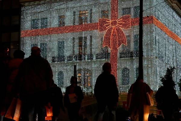 People walk in front of a Christmas decorated electronic store at Syntagma square in Athens, Gr ...