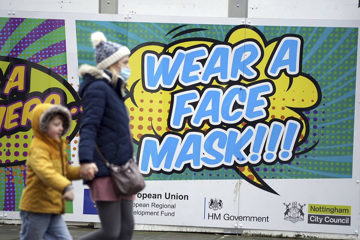 People walk past a billboard inviting citizens to wear face masks to curb the spread of COVID-1 ...