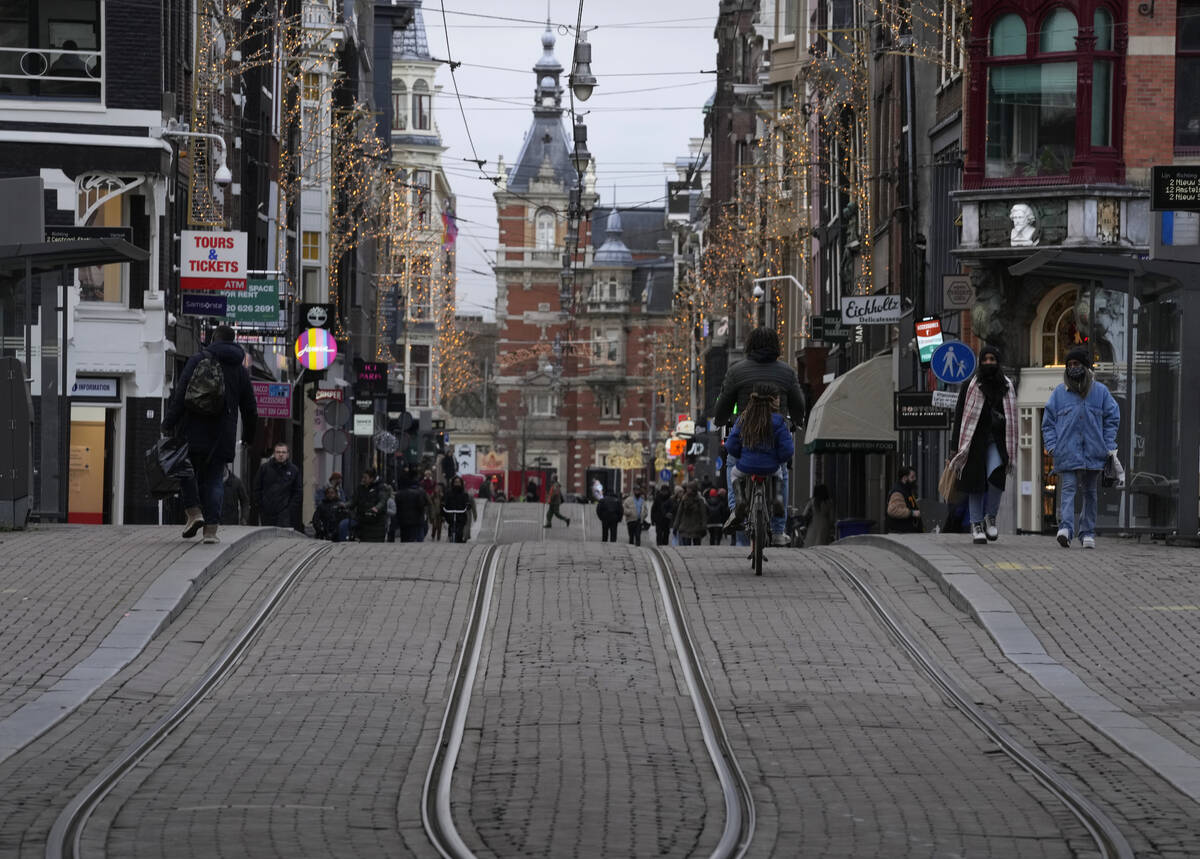 People walk down a normally bustling shopping street in the center of Amsterdam, Monday, Dec. 2 ...