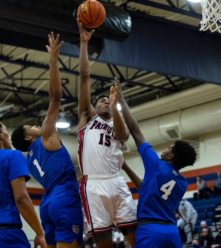 Liberty HighÕs Aaron Price (15) goes for the hoop between Bishop GormanÕs James Free ...