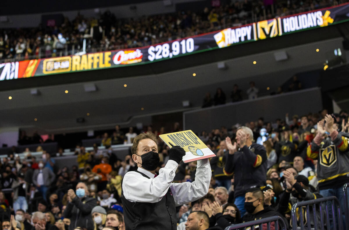 A Golden Knights usher holds a mask up sign during an NHL hockey game against the Tampa Bay Lig ...