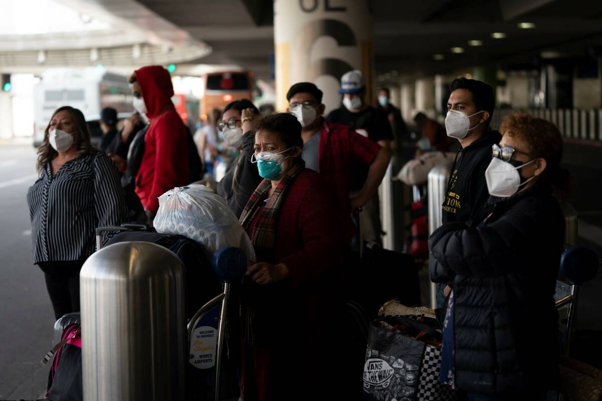 Travelers wait for a shuttle but to arrive at the Los Angeles International Airport in Los Ange ...