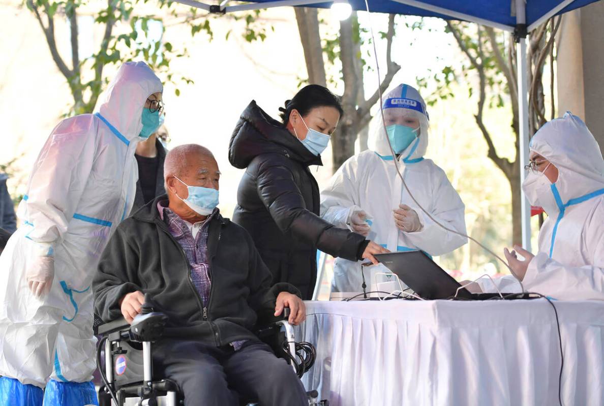 In this photo released by China's Xinhua News Agency, people register for tests at a COVID-19 t ...