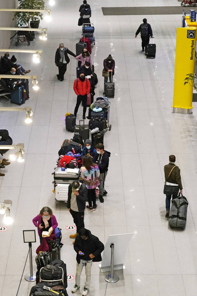 Travelers wait in line to be tested for COVID-19 at Logan Airport, Tuesday, Dec. 21, 2021, in B ...