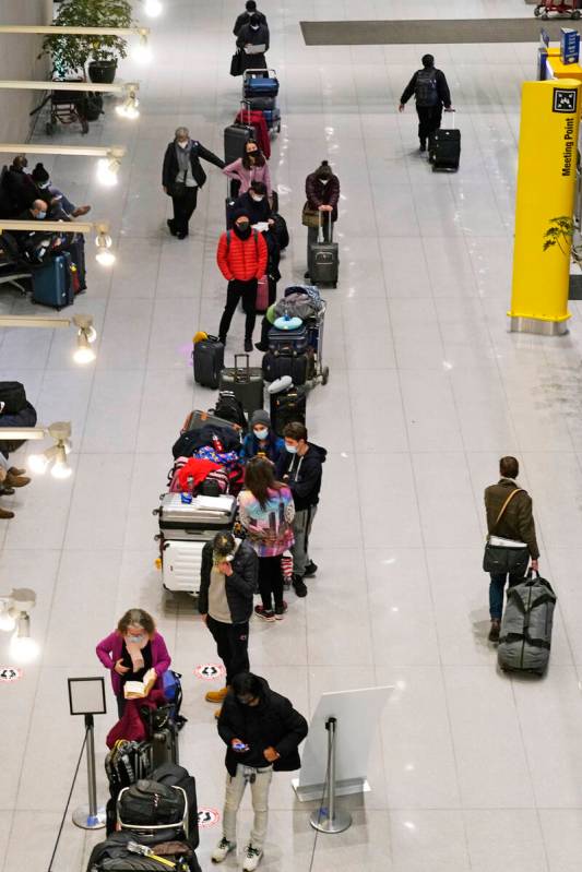 Travelers wait in line to be tested for COVID-19 at Logan Airport, Tuesday, Dec. 21, 2021, in B ...