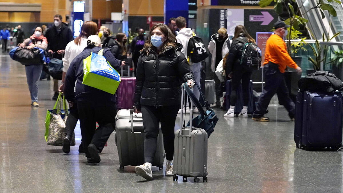 Travelers trek through Terminal E at Logan Airport, Tuesday, Dec. 21, 2021, in Boston. At leas ...
