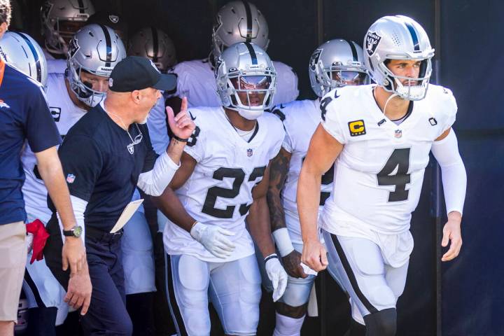 Raiders interim head coach Rich Bisaccia runs onto the field with his players to face the Denve ...