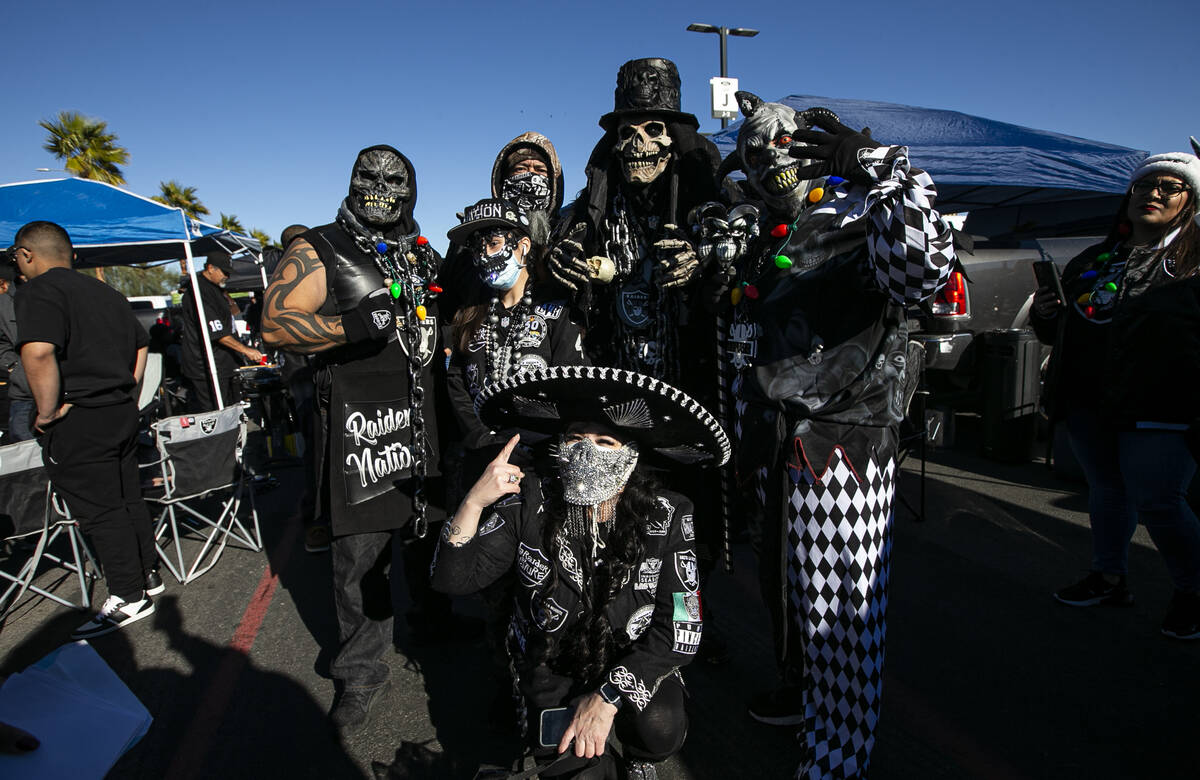 Raiders fans pose for a picture while tailgating before an NFL football game against the Bronco ...