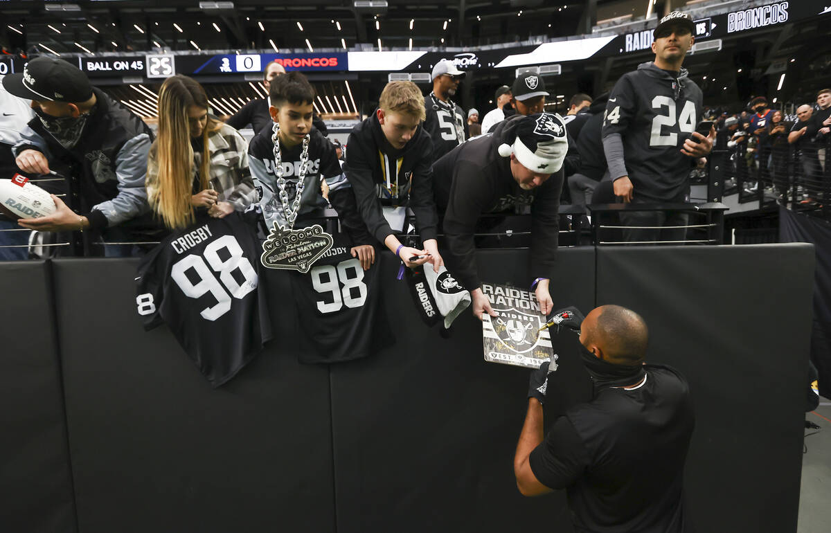 Raiders outside linebacker K.J. Wright signs items for fans before an NFL football game against ...