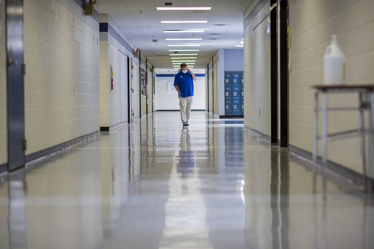 FILE - A middle school principal walks the empty halls of his school as he speaks with one of h ...