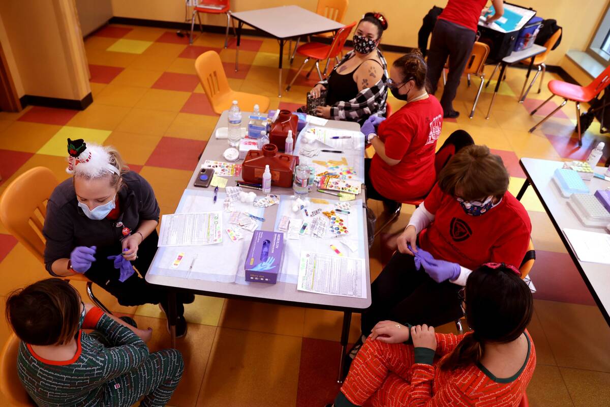 Amber Salmo, top, gets a COVID-19 vaccination with her daughter Skylar Salmo, 9, right, and nep ...