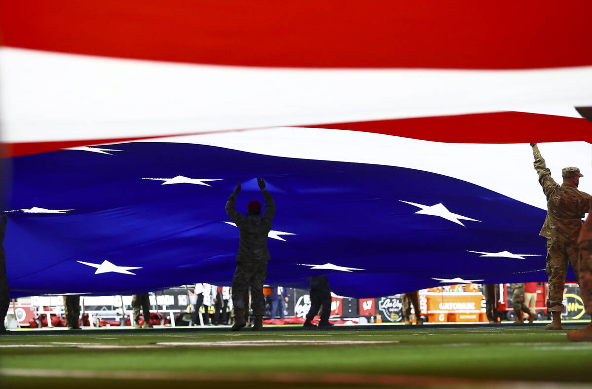 Members of the military and law enforcement display the U.S. flag across the field before the L ...