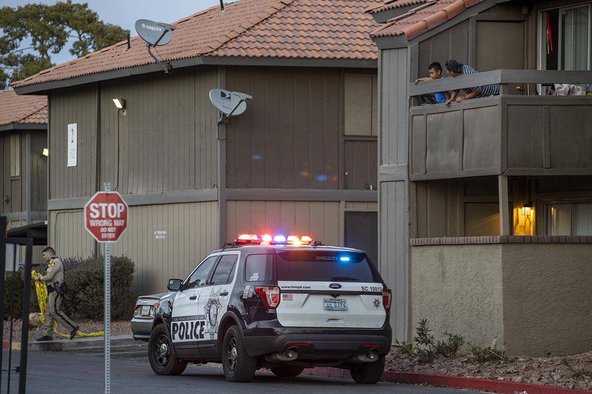 Residents look down on a Metro vehicle as officers conduct a homicide investigation at the Sola ...