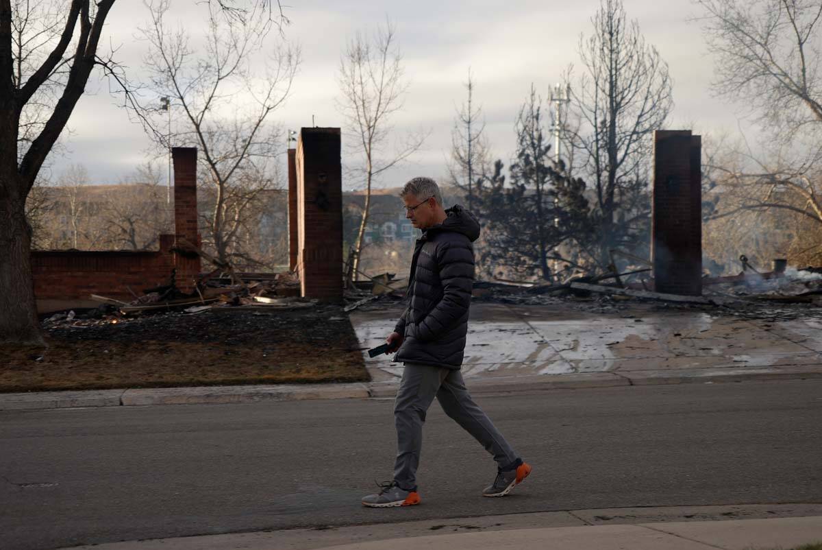 Dan Bruder walks past burned homes in his neighborhood, Dec. 31, 2021, in Superior, Colo. An es ...