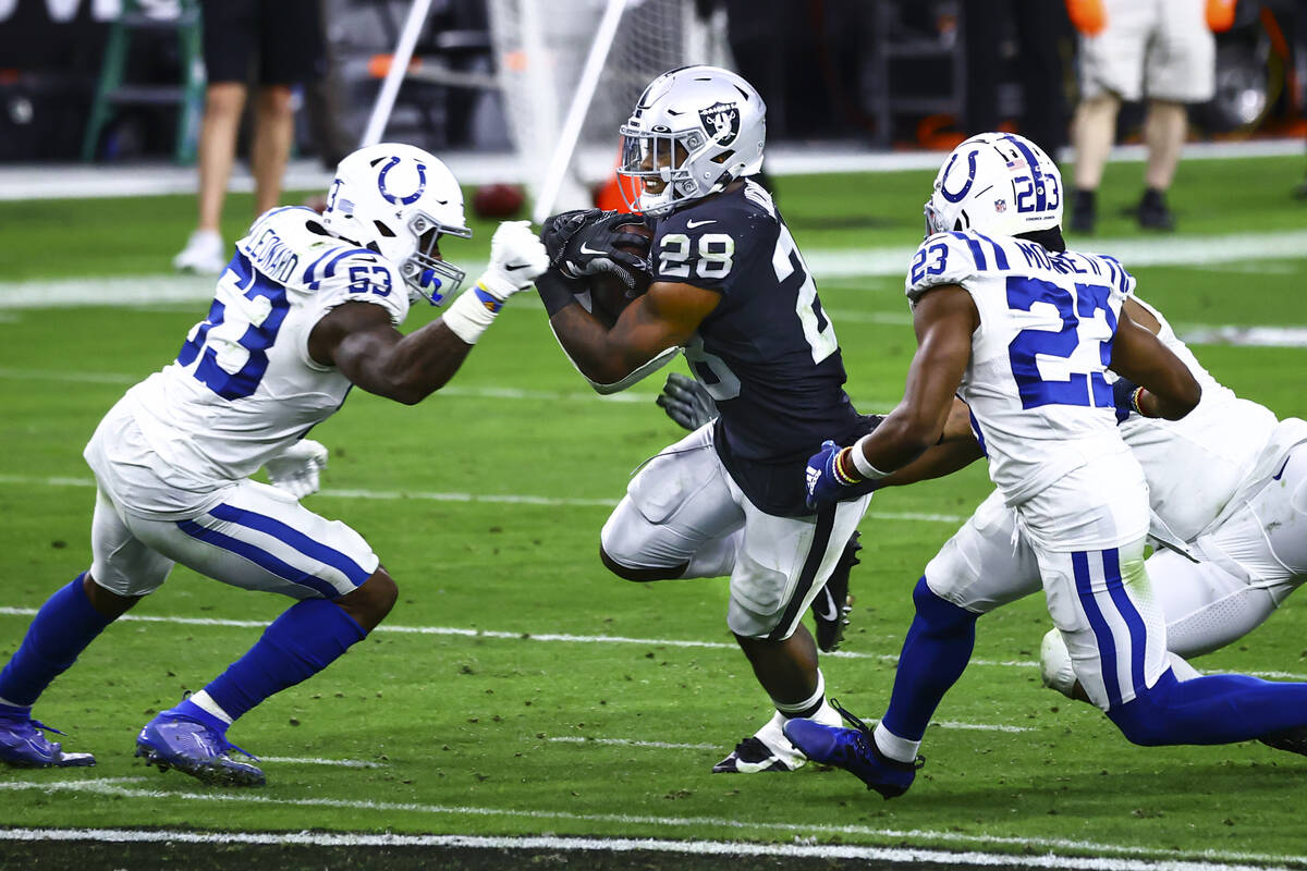 Raiders running back Josh Jacobs (28) tries to get past Indianapolis Colts defense, including o ...