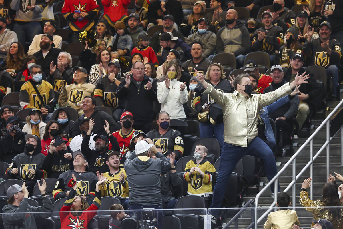 Entertainer Cameron Hughes, right, hypes up the crowd during the first period of an NHL hockey ...