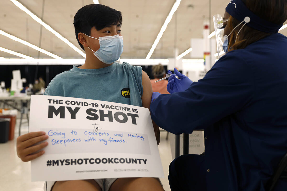 Lucas Kittikamron-Mora, 13, holds a sign in support of COVID-19 vaccinations as he receives his ...